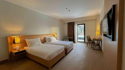 a hotel room with a bed and a television at Swiss-Belhotel Manokwari in Manokwari