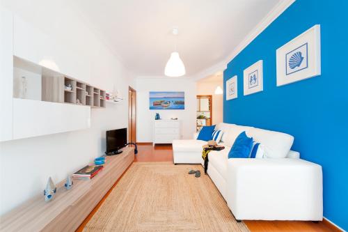 a living room with a white couch and a blue wall at Ericeira Apartment - Blue Sea in Ericeira