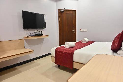 a hotel room with a bed and a flat screen tv at Majestic Grand in Madurai