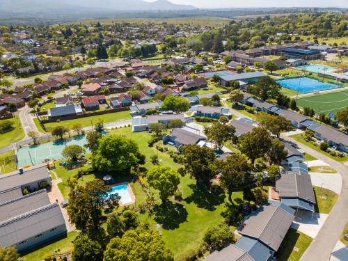 une vue aérienne sur une banlieue avec des maisons et un court de tennis dans l'établissement Pine Lodge George, à George