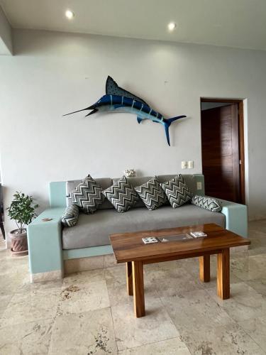 a living room with a couch with a shark on the wall at El Nido Casa 4 in Zihuatanejo