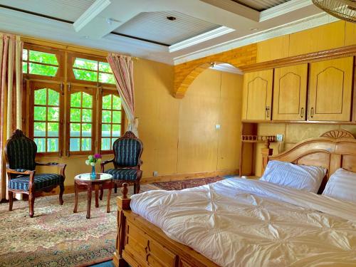 a bedroom with a large bed and two chairs at Gangchen Guest House in Skardu