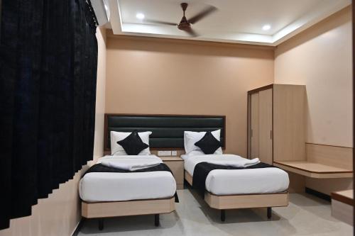 a bedroom with two beds and a cabinet at Majestic Grand in Madurai