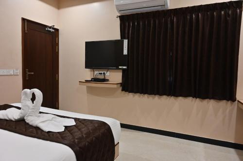 a hotel room with a bed and a flat screen tv at Majestic Grand in Madurai
