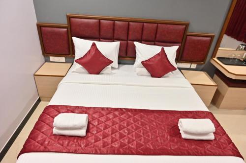 a bedroom with a large bed with red pillows at Majestic Grand in Madurai