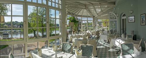a restaurant with white tables and chairs and windows at Dorint Parkhotel Meißen in Meißen