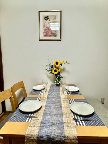 a dining room table with plates and a vase of flowers at 市中山居 大阪站梅田站 阪急商圈 中畸町站步行3分钟 超大獨棟别墅 适合家庭团体 in Osaka