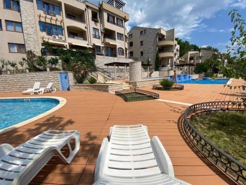 une piscine avec des chaises longues blanches à côté d'un bâtiment dans l'établissement Apartment Steven, à Herceg-Novi