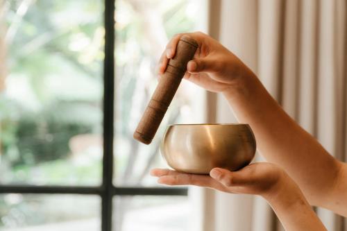 a person holding a coffee cup with a cinnamon stick at Amarea Resort & Spa Ubud by Ini Vie Hospitality in Ubud
