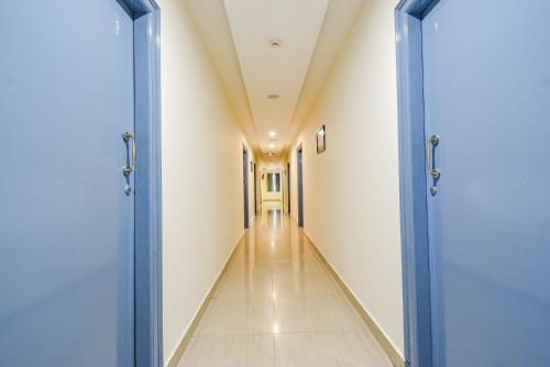 an empty corridor in a hospital with two blue doors at FabHotel Broholic Prime Suites - Nr Nexus Mall, Kukatpally in Kondapur