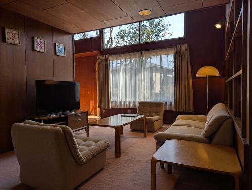 a living room with a couch and a tv at Kawaguchiko Hotel in Fujikawaguchiko