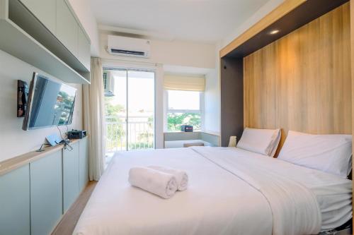a bedroom with a large white bed with a window at Best Deal and Comfort Studio Citra Living Apartment By Travelio in Jakarta