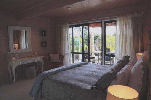 1 dormitorio con cama, mesa y ventana en Two Bare Feet, en Waihi Beach