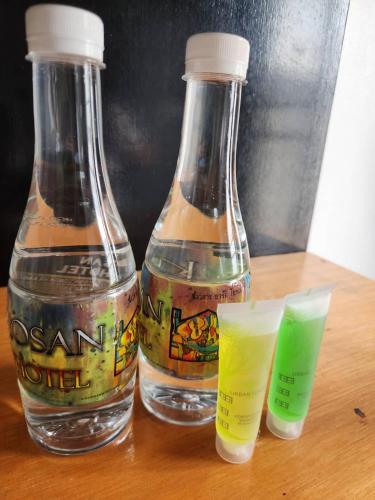 two bottles of water sitting on a wooden table at Khaosan Art Hotel in Bangkok