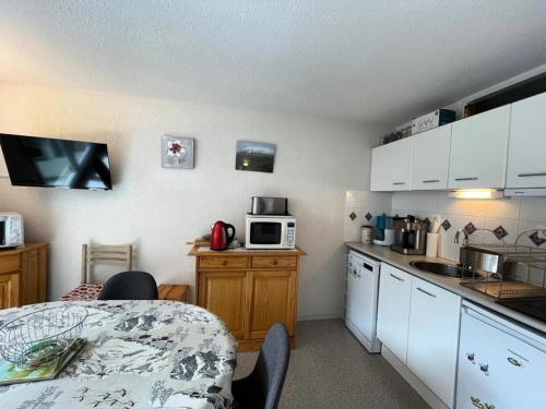 une cuisine avec des armoires blanches et une table avec un micro-ondes dans l'établissement Résidence Le Vignemale - APPARTEMENT 4-6 personnes Résidence VIGNEMALE MAE-4821, à Saint-Lary-Soulan