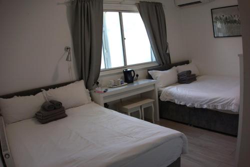 a bedroom with two beds and a desk and a window at Abbey Point Hotel in London