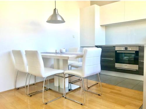 a kitchen with a white table and white chairs at COZY PLACE NEAR BUS AND RAILWAY STATION with common kitchen, bathroom and toilet in Zagreb