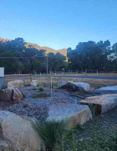 a garden with rocks and a tree in the middle at Jimmara House Modern central holiday home in Halls Gap