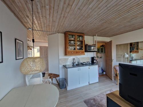 una cocina con armarios blancos y una mesa en una habitación en Lillebo fred og ro, en Græsted