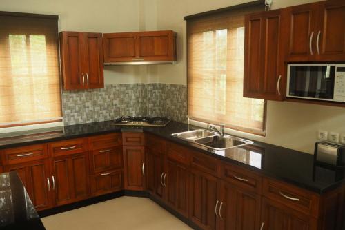 a kitchen with wooden cabinets and a sink at The Gecho Inn Country in Jepara