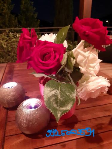 a vase of roses and two candles on a table at casa cappellino in Vicovaro