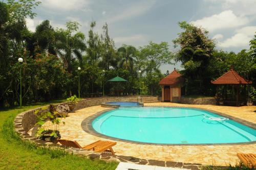 a large swimming pool with chairs and a gazebo at The Gecho Inn Country in Jepara