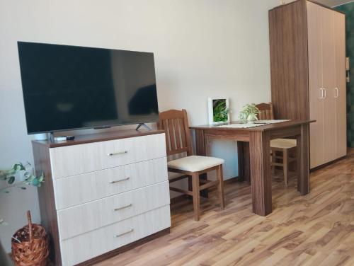 a living room with a television on a dresser with a desk at Studio in Sea Breeze Complex Sveti Vlas in Sveti Vlas