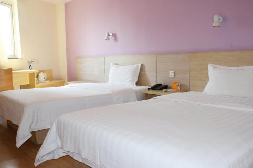 a hotel room with two beds with white sheets at 7Days Inn Hefei Railway Station Plaza in Hefei