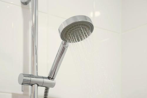 a shower head with water coming out of it at Studio-Apartment Piccolino 26 in Timmendorfer Strand