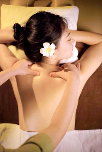 a woman laying on a bed with a flower in her hair at Da Nang - Mikazuki Japanese Resorts & Spa in Da Nang
