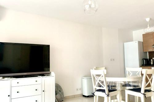 un salon avec une télévision, une table et des chaises dans l'établissement Villa Paloma, à Antibes