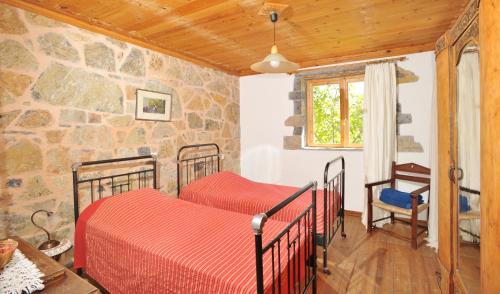 two beds in a room with a stone wall at Giannikaki's Villas in Prína