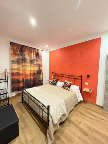 a bedroom with a large bed with a red wall at 8380 La Cantina di Piero&Netta in Montemerano