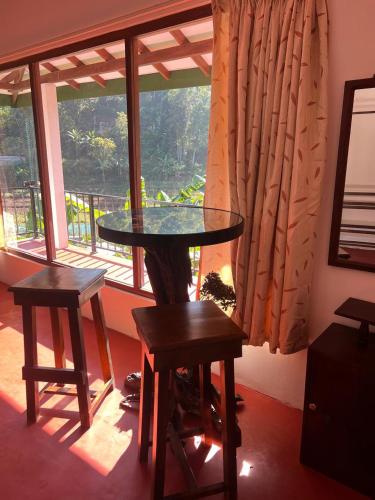 a table and two stools in a room with a window at Moban House in Diyatalawa