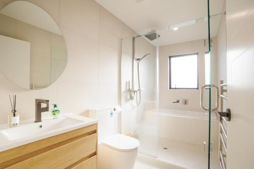 a bathroom with a shower and a toilet and a sink at Stylish 4BR Home, Netflix, Walk to Eateries and Schools in Auckland