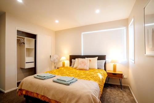 a bedroom with a bed with two towels on it at Stylish 4BR Home, Netflix, Walk to Eateries and Schools in Auckland
