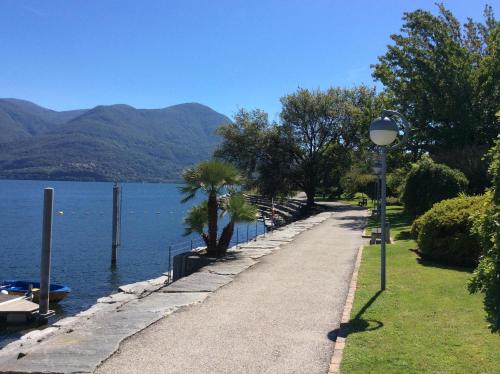 a path next to a lake with a street light at Casa Felice by Fewotessin in Brissago