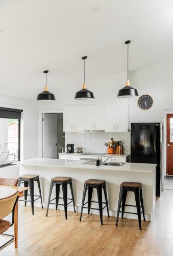 a kitchen with white cabinets and a large island with stools at Jimmara House Modern central holiday home in Halls Gap