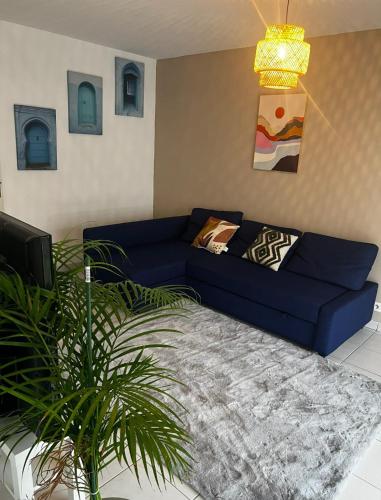 - un canapé bleu dans un salon avec une plante dans l'établissement ZEHNITH Strasbourg tramway, à Strasbourg