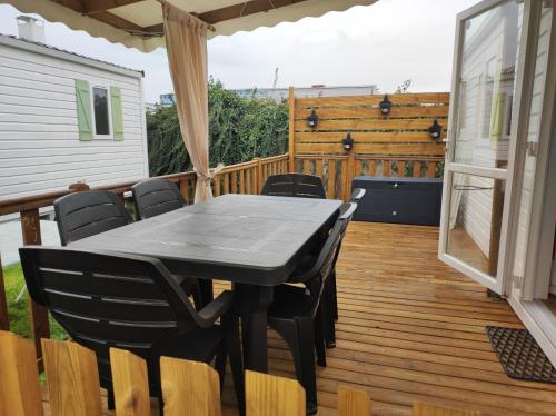 une table et des chaises noires sur une terrasse dans l'établissement Mobil home 6 personnes, à Boofzheim
