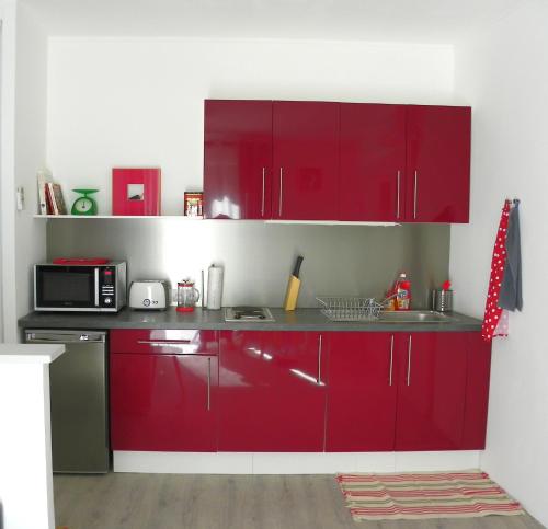 a kitchen with red cabinets and a microwave at Provencal Vintage Cocoon in LʼIsle-sur-la-Sorgue