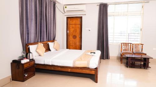 a bedroom with a bed and a table and a window at Hotel Royal Beltola in Guwahati