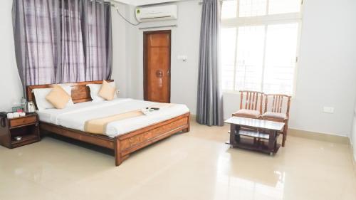 a bedroom with a bed and a chair at Hotel Royal Beltola in Guwahati