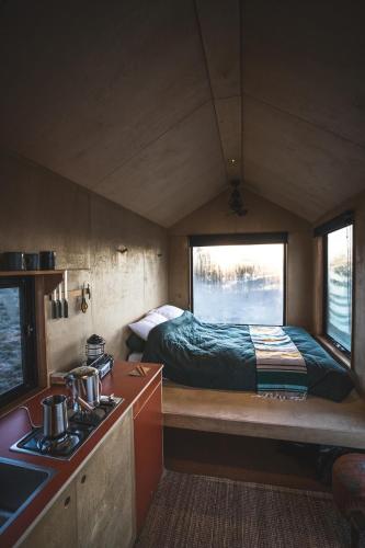 a small room with a bed and a kitchen with a stove at Remote Off-Grid Cabin in the Wilderness - Jude in Warrenmang