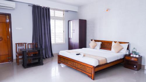 a bedroom with a bed and a chair and a window at Hotel Royal Beltola in Guwahati