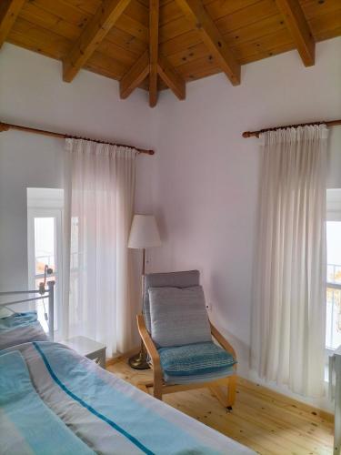 a bedroom with a bed and a chair and a window at Alexandros Traditional House in Ialysos