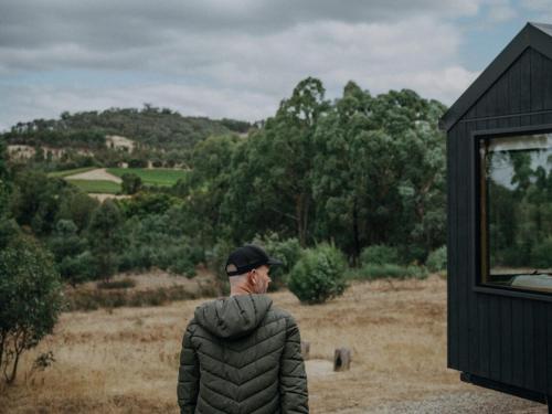 a man standing in a field looking out over a hill at Remote Off-Grid Cabin in the Wilderness - Jude in Warrenmang