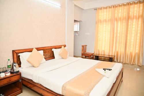 a bedroom with a large white bed and a window at Hotel Royal Beltola in Guwahati