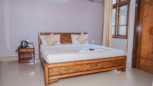 a bedroom with a bed with a wooden frame at Hotel Royal Beltola in Guwahati