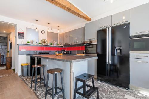 - une cuisine équipée d'un réfrigérateur noir et de tabourets dans l'établissement Le Rive Gauche - Au cœur du centre historique, à Narbonne